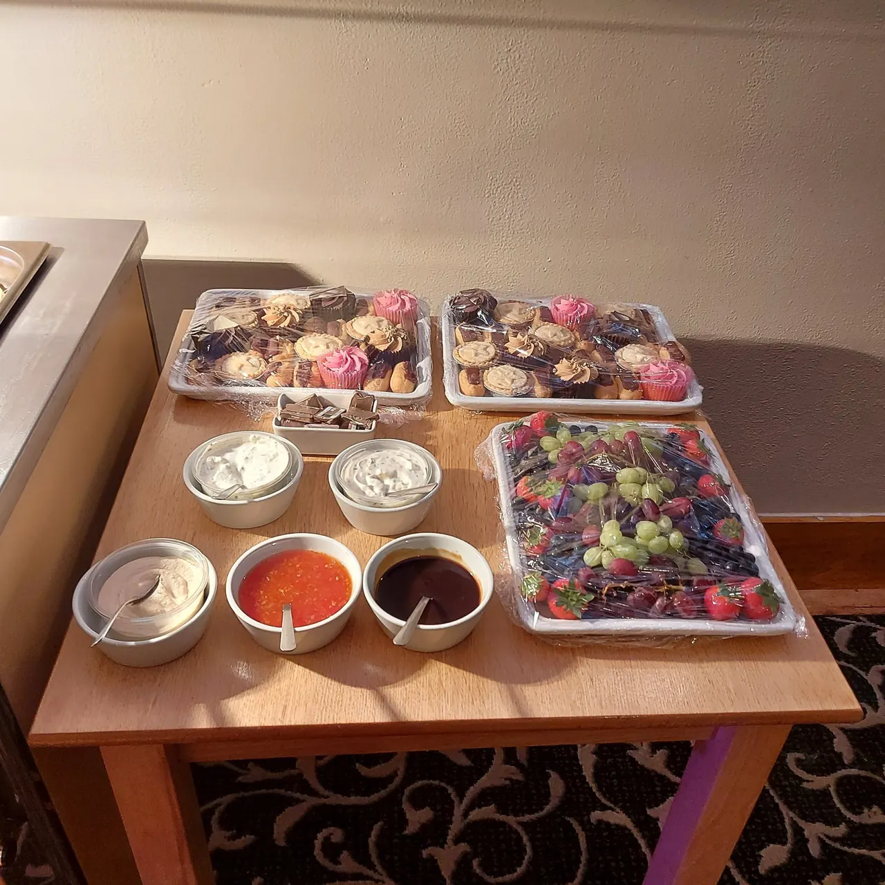 Dessert table of mini cakes, doughnuts, fruit and sauces