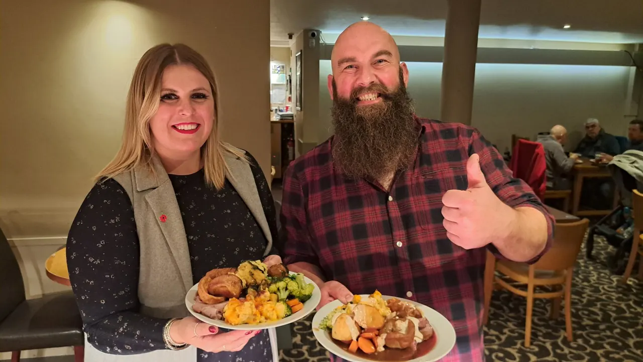 Two smiling guests holding Sunday carvery plates at Enigma